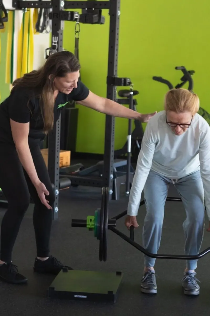A Calibrated trainer coaching a client through a trap-bar lift in the Los Altos studio